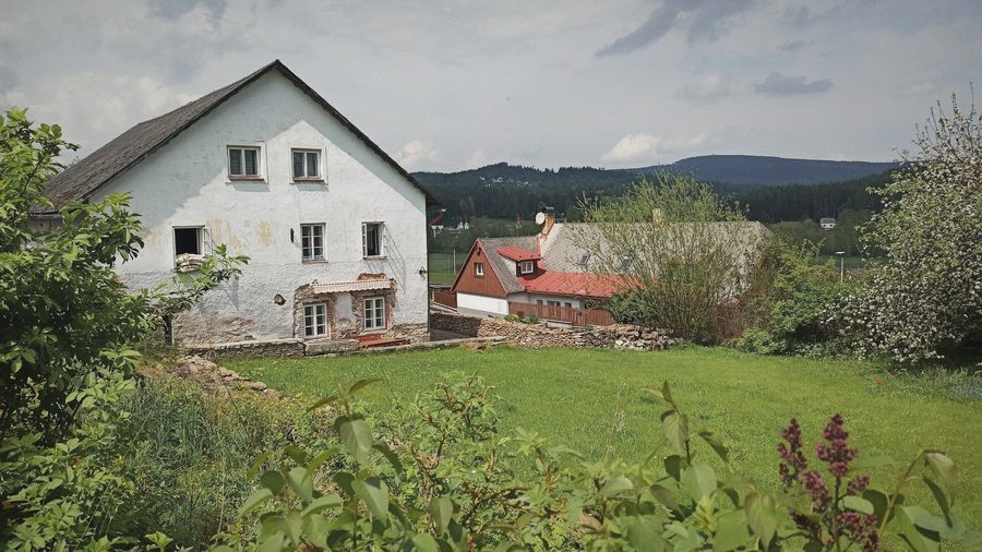 Chalupa a šumavské kopce na obzoru