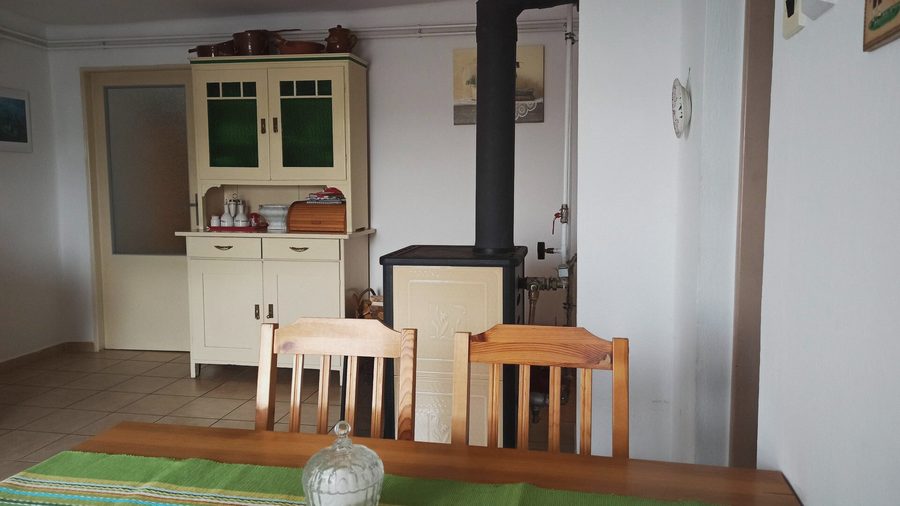 Kamna na dřevo vedle kredence a jídelního stolu